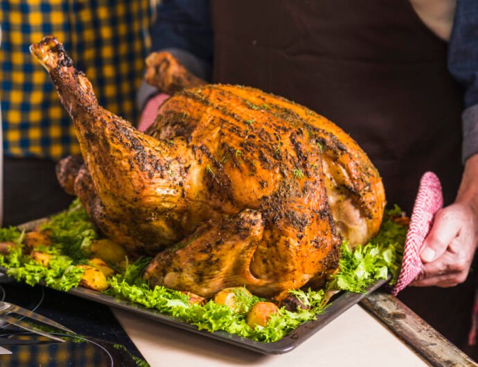human-hand-holding-tray-with-roasted-ham