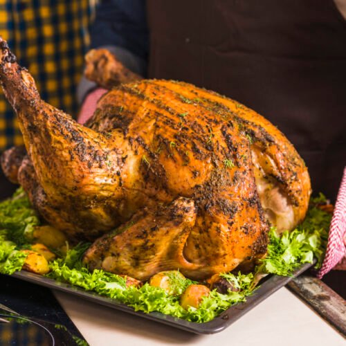 human-hand-holding-tray-with-roasted-ham